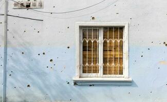 The buildings were hit by shelling. Boarded up windows and damaged facade. Preparing the house for hostilities and war. Destroyed houses in the city during the war in Ukraine. photo