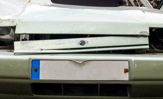 The front of the car with damage to the bumper after the accident. Empty license plate. Close-up of the surface of the license plate in front of the car, square license plate of the car. photo