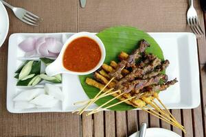 Satay chicken beef with peanut sauce diced onion cucumber ketupat rice cake photo