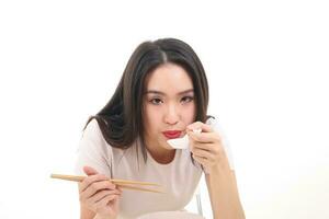 Beautiful young south east Asian woman holding chinese empty chopstick soup spoon bowl utensil pretend acting posing see eat taste feed offer satisfaction yummy white background happy blow cool photo