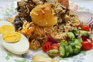 hogar estilo Carne de cordero kacchi Biryani con patata picar tomate Pepino cebolla ensalada en antiguo estilo plato foto