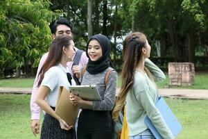 joven asiático malayo chino hombre mujer al aire libre parque libro archivo carpeta ordenador portátil computadora teléfono sentar estar estudiar mezclarse foto