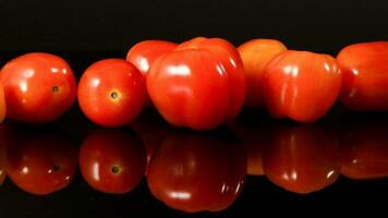 Fresh ripe small shiny red tomato on black background photo