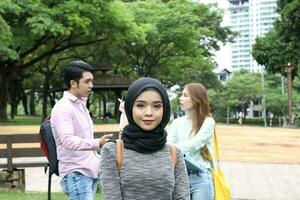 joven asiático malayo chino hombre mujer al aire libre parque libro archivo carpeta ordenador portátil computadora teléfono sentar estar estudiar mezclarse foto