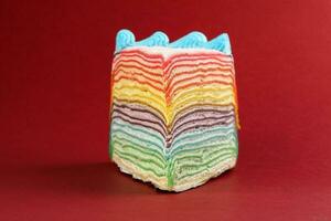 Rainbow crepe layer cake on red background photo