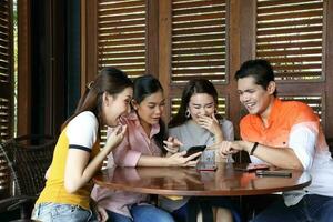 Group young asian malay man woman at rustic wooden cafe table meet talk discuss business study check see read massage photo on phone