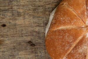 Freshly baked bread loaf round on rustic wood background photo