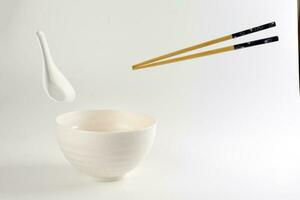 Empty oriental Japanese Chinese soup bowl spoon chopstick elevated flying in air off white photo