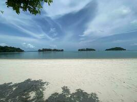 daylight wind small wave on ocean sea water near the beach at straits of Melaka small islands and boats floating photo