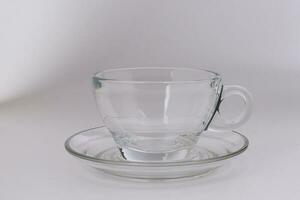 Empty transparent glass see through coffee tea cup saucer on white background photo