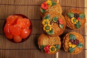 Mid autumn festive colorful flower decorated moon cake making ingredients salted egg yolk cut slice on blue ceramic plate background on bamboo food mat photo