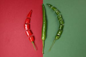 whole green red chilli pepper on green red paper background cut pieces seeds photo