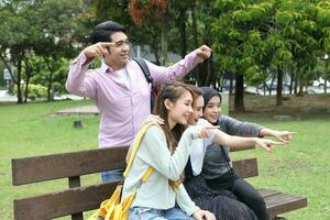 joven asiático malayo chino hombre mujer al aire libre parque libro archivo carpeta ordenador portátil computadora teléfono sentar estar estudiar mezclarse foto