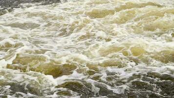 River rapids. Close up abstract background of falling water. Water flows over river rocks. A beautiful powerful stream of a stormy mountain river. The river rushes with fast-flowing water. video