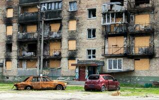 The car that burned down after the bombing of the city stands in the courtyard of a destroyed house. War between Russia and Ukraine. Fragments of a car after artillery shelling. photo