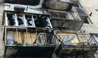 Burnt apartments in a multi-storey residential building, the consequences of the war in Ukraine. Buildings damaged by shells. A bombed-out apartment building after an airstrike. photo