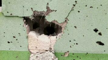 des trous de balles et shrapnel dans le mur sur le de face doubler. cicatrices de guerre. béton mur de une Résidentiel bâtiment avec nids-de-poule et des trous de fusillade. conséquences de le guerre dans Ukraine. video