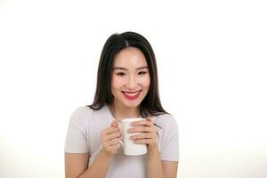 Beautiful young south east Asian woman holding white coffee tea cup emotion expression on white background look at camera smile photo