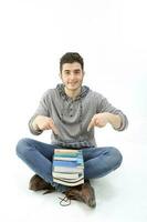 Middle eastern Caucasian young in casual dress sit on floor pointing at books happy smile expression on white background photo