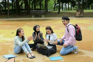 joven asiático malayo chino hombre mujer al aire libre parque libro archivo carpeta ordenador portátil computadora teléfono sentar estar estudiar mezclarse foto