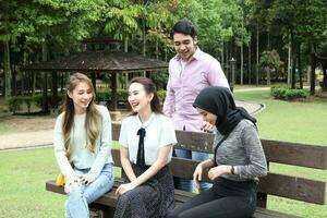 joven asiático malayo chino hombre mujer al aire libre parque libro archivo carpeta ordenador portátil computadora teléfono sentar estar estudiar mezclarse foto