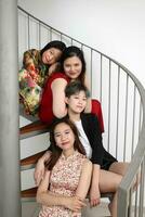 Young southeast asian woman group sitting on indoor spiral staircase happy enjoy fun look fun crazy funny photo