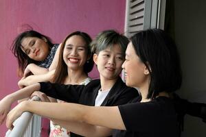 Young southeast asian woman group on balcony veranda standing side by side enjoying view talking happy looking photo