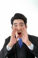 Southeast Asian young office business man wearing suit fist hand on mouth calling shouting announcing expression look at camera on white studio background photo