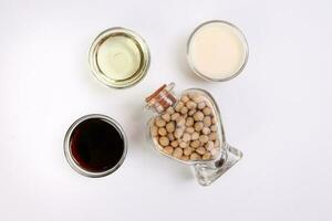 Soya beans in a hart shape glass bottle soya sauce milk oil in glass bowl on white background photo