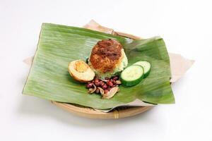 Nasi Lemak fragrant rice cooked in coconut milk served with sambal friend peanut anchovy boiled egg packed in banana leaf on round bamboo plate on white background photo