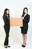 Two young asian malaysian business office woman holding blank copy text space sign board on white background photo