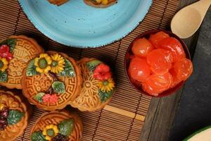 Mid autumn festive colorful flower decorated moon cake making ingredients salted egg yolk cut slice on blue ceramic plate background on bamboo food mat photo