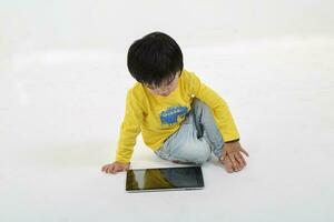 South East Asian young boy child playing tablet tab computer pc on white background photo