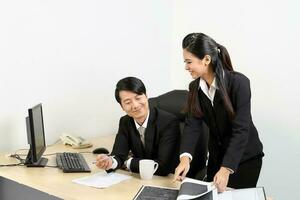 Young Asian male female wearing suit sitting at office desk see show discuss computer document photo