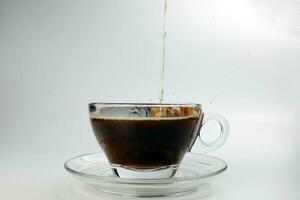 dark Coffee poring dripping splash shadow liquid swirl in glass cup saucer on white background stop motion photo