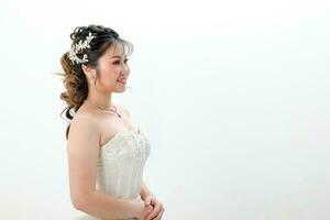 Young Asian woman in white dress hair done with crown on white background photo