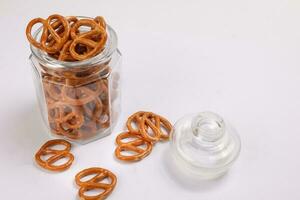 Pretzel cracker in a glass jar pouring dropping on white background photo