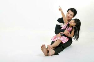 South East Asian father daughter child playing hugging sting on floor lap talking pointing up on white background photo