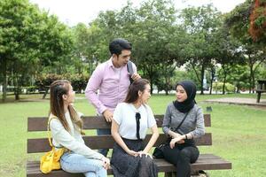 joven asiático malayo chino hombre mujer al aire libre parque libro archivo carpeta ordenador portátil computadora teléfono sentar estar estudiar mezclarse foto