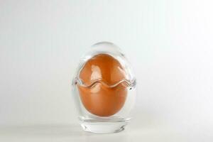 Egg in egg shape glass container protection shell on white background safety security photo