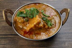 Haleem stew wheat barley lentils mutton goat chicken beef meat bone spice served in a copper brass pot over rustic wood background photo