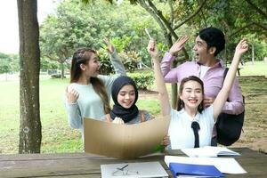 joven asiático malayo chino hombre mujer al aire libre parque libro archivo carpeta ordenador portátil computadora teléfono sentar estar estudiar mezclarse foto