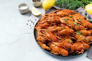 top view of cooked crawfish platter with lemons and spices on cement background photo