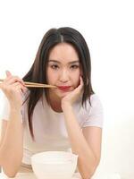 Beautiful young south east Asian woman holding chinese empty chopstick soup spoon bowl utensil pretend acting posing see eat taste feed offer satisfaction yummy white background happy photo