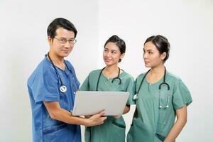 Young Asian male female doctor wearing apron uniform tunic stethoscope holding laptop talk discuss photo