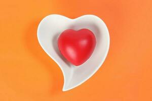 Hart Love shape plastic rubber object on white plate orange background photo