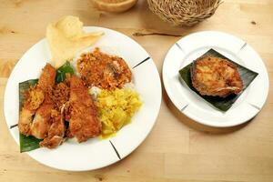 Traditional Malaysian Indian food white rice cabbage vegetable meat deep fried chopped chicken leg topped up with spicy mix gravy wood table background photo