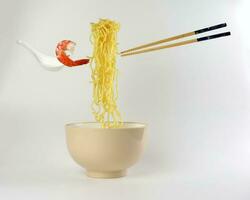 Yellow seafood prawn noodle soup elevated flying suspended in air with soup spoon and chopstick on white background photo