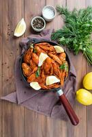 cooked crawfish in black saucepan with lemons and spices on wooden background photo