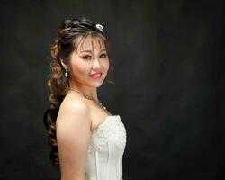 Young Asian woman in white dress hair crown on black background photo